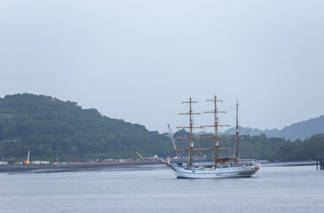 Elegant three-masted tall ship cruising toward the Pacific Ocean, combining traditional sailing technology with a scenic tropical maritime landscape. © Mariusz