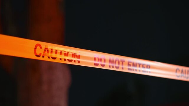 Caution do not enter tape at night with police lights flashing blocking restricted area creating crime scene atmosphere and access limitation