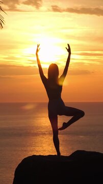 Woman Practicing Yoga Tree Pose Silhouette at Golden Sunset