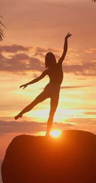 Woman Practicing Yoga Silhouette on a Rock at Golden Sunset