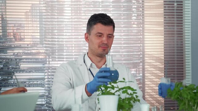 A group of scientists in white lab coats and blue gloves conduct plant research using laboratory glassware inside a modern facility overlooking a cityscape.
