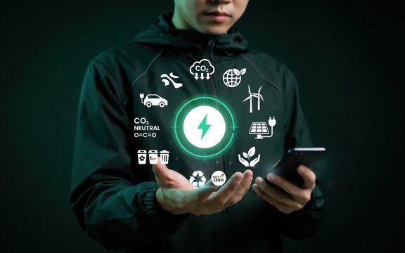Green energy and sustainability concept photo. Man holding smartphone with glowing eco icons. Clean technology and renewable power.