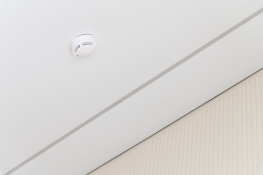 Smoke detector on white ceiling in room corner