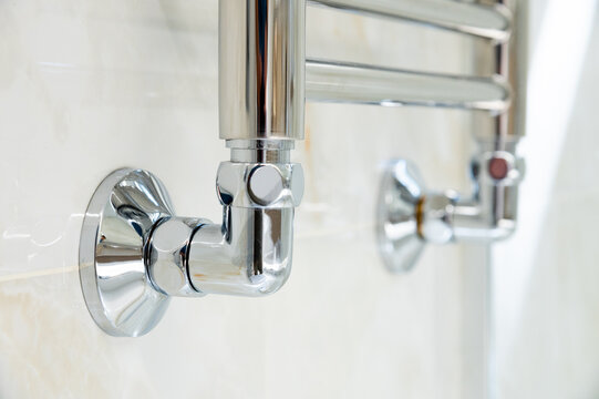 Chrome heated towel rail mounted on a tiled wall