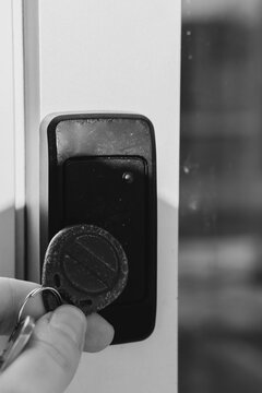 A person uses an RFID key fob to access a secure door via an electronic card reader, symbolizing modern security technology.