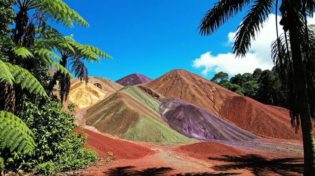 Scenic view of the Seven Coloured Earths geological formation on a sunny day with palm trees, blue sky