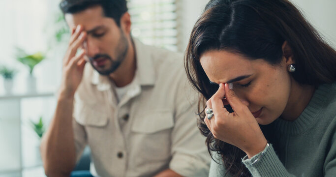 Unhappy young Latin man and woman discussing finance debt and bankruptcy on the couch at home. Marriage divorce difficulty, serious relationship separation problem, couple counseling therapy concept.