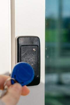 A person uses an RFID key fob to access a secure door via an electronic card reader, symbolizing modern security technology.