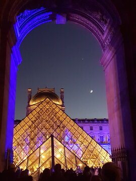 La pyramide du Louvre vue de nuit depuis l'entr&eacute;e de la rue de RIvoli du Palais du Louvre avec la lune se levant au-dessus de la pyramide (Paris, France)