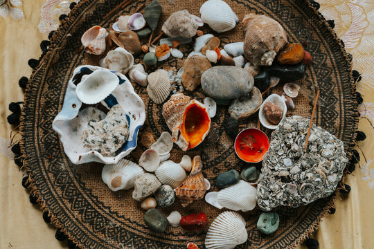 Collection of sea shells, smooth stones, and small candles on a textured decorative tray