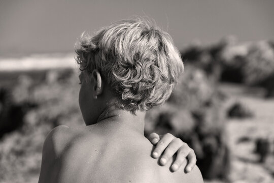 rear view of of young boys blond curly hair at the beach