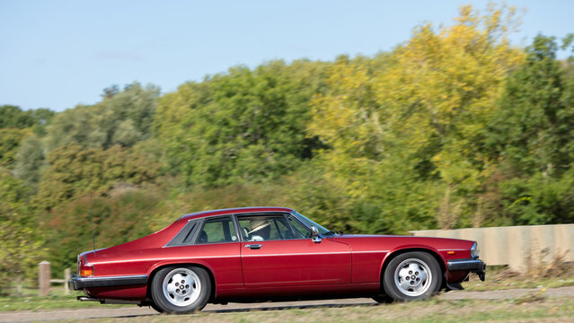 Milton Keynes; UK - Sept. 20th 2026: 1987 red 1980s Jaguar xjs classic car driving on a British road