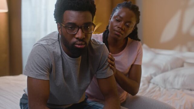 African American married couple arguing at home bedroom indoors guilty wife comforting husband asking forgiveness annoyed man rejecting family conflict quarrel crisis relationship problem late night