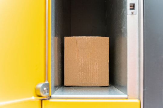 Cardboard parcel inside open parcel locker compartment ready for customer pickup