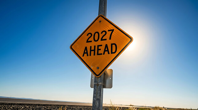 Road sign reading 2027 ahead against bright blue sky and sunlit horizon