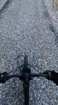 Vertical POV Of Cyclist Riding Mountain Bike On Gravel Forest Road