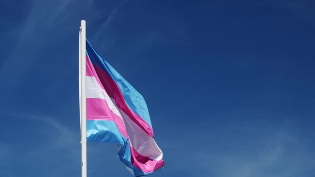 Trans flag colors and transgender pride flag wave above Lisbon, Portugal for an LGBT equality celebration, with windblown fabric during an outdoor celebration