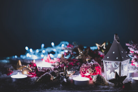 Christmas background with burning candles, ornaments and snow on blue