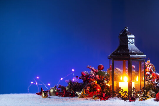 Christmas background with burning candles, ornaments and snow on blue