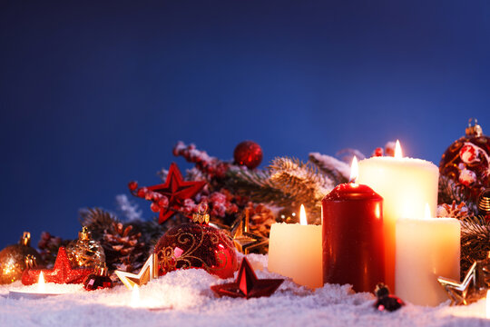 Christmas background with burning candles, ornaments and snow on blue