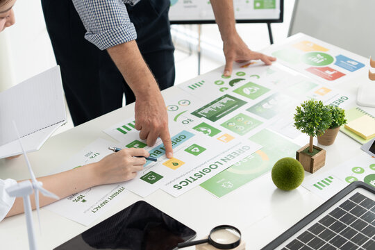 A diverse business team analyzing environmental charts and graphs in a collaborative meeting to create sustainable strategies in a modern office.