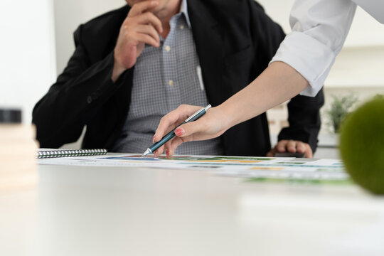 A diverse business team analyzing environmental charts and graphs in a collaborative meeting to create sustainable strategies in a modern office.