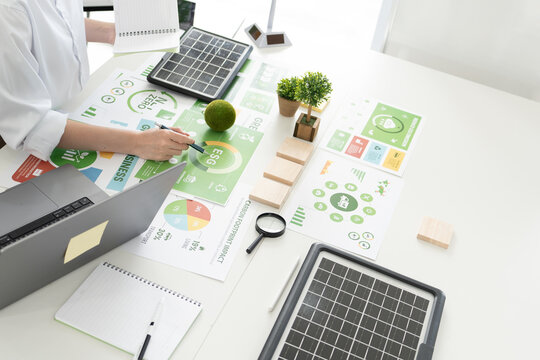 A diverse business team analyzing environmental charts and graphs in a collaborative meeting to create sustainable strategies in a modern office.