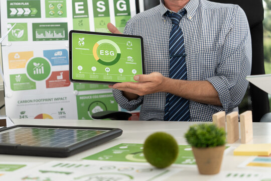 A diverse business team analyzing environmental charts and graphs in a collaborative meeting to create sustainable strategies in a modern office.