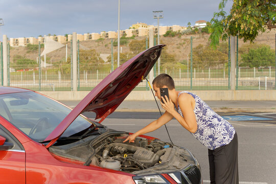 Woman identifying engine problem during roadside phone call