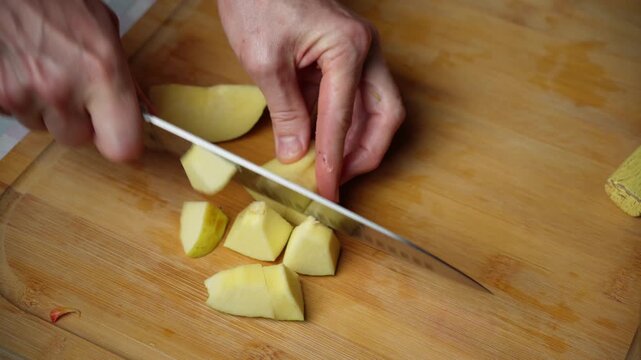 Cutting Quince Into Small Pieces. Fresh quince is cut into small pieces on a wooden cutting board for a homemade turkey and vegetable dinner.