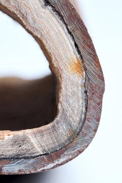 Section of industrial hot water boiler pipe with limescale deposits inside wall, reducing heat transfer efficiency, causing energy loss, corrosion, plumbing blockage, equipment failure