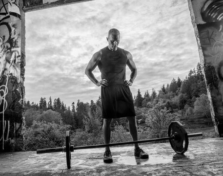 Muscular white man preparing to lift barbell during outdoor workout