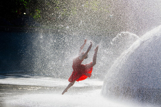White dancer leaping through water fountain spray