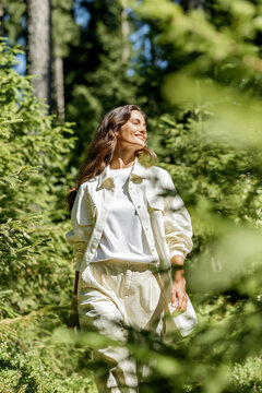 Woman walking peacefully through sunlit forest path. Digital detox, mindfulness meditation walk, natural wellness lifestyle in nature.