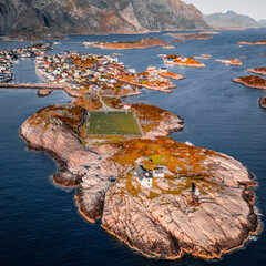 Aerial drone view of Henningsvaer football field and fishing village on rocky islands surrounded by ocean water in Lofoten Norway © Quality by Simon