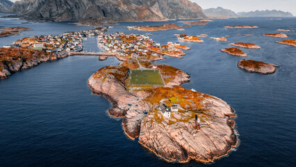 Aerial drone view of Henningsvaer football field and fishing village on rocky islands surrounded by ocean water in Lofoten Norway © Quality by Simon
