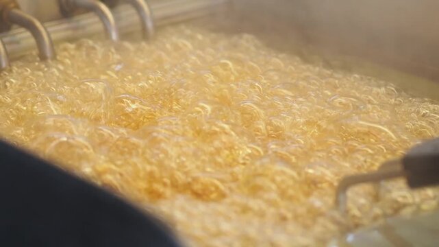 Close up shot of french fries cooking in hot oil in deep fryer bubbling aggressively