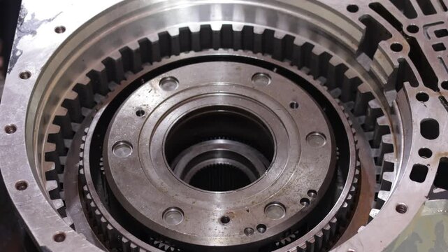 A mechanic installs friction and reaction clutch plates into a heavy transmission housing indoors.