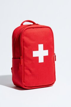 Red first aid kit backpack with white cross isolated on white studio view