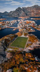 Vertical aerial drone view of the famous Henningsvaer football field on a rocky island surrounded by ocean and mountains in Lofoten Norway © Quality by Simon