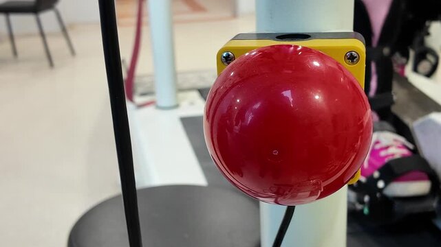 Red emergency stop button on industrial equipment in modern laboratory or gym setting