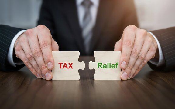 Businessman holding two wooden jigsaw puzzle pieces with tax relief text