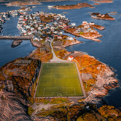 Aerial drone view of the famous Henningsvaer football field and fishing village on rocky islands surrounded by ocean water in Lofoten Norway © Quality by Simon
