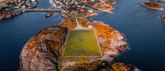 Aerial drone view of the famous Henningsvaer football field and fishing village on rocky islands surrounded by ocean water in Lofoten Norway © Quality by Simon