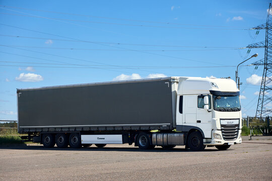 Berlin, Germany - August, 13 2026: White DAF XF truck with grey Krone semi trailer parked outdoors under clear blue sky near power line pylons on sunny day, commercial cargo transport logistics