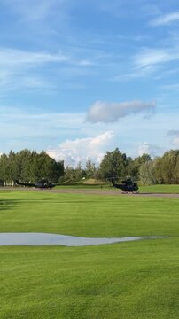 Military helicopters on a golf course with soldiers disembarking and preparing for action, showcasing a unique juxtaposition of military presence in a recreational setting