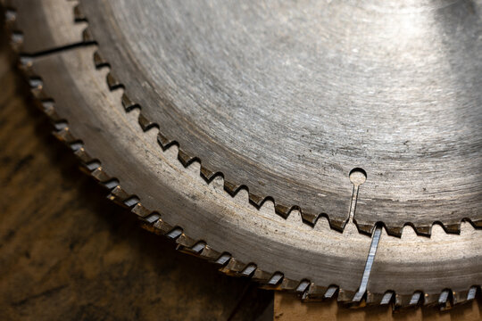 Macro close-up of circular saw blades showing carbide teeth, gullets and expansion slots designed for efficient sawdust removal, heat control and precise woodworking cuts.