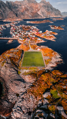 Aerial drone view of the famous Henningsvaer football field and fishing village on rocky islands surrounded by ocean water in Lofoten Norway © Quality by Simon