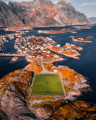 Aerial drone view of the famous Henningsvaer football field and fishing village on rocky islands surrounded by ocean water in Lofoten Norway © Quality by Simon