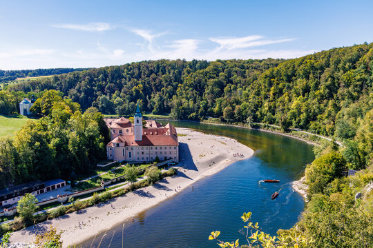 High angle view of historic Weltenburg Abbey on Danube river bend surrounded by dense green forest near Kelheim, iconic Bavarian travel destination concept